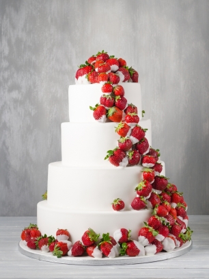 Белоснежный многоярусный свадебный торт со свежей спелой клубникой в шоколаде