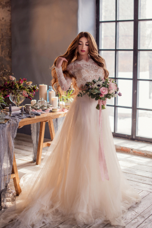 Портрет невесты в платье с букетом в лофте с красивым цветочным декором 