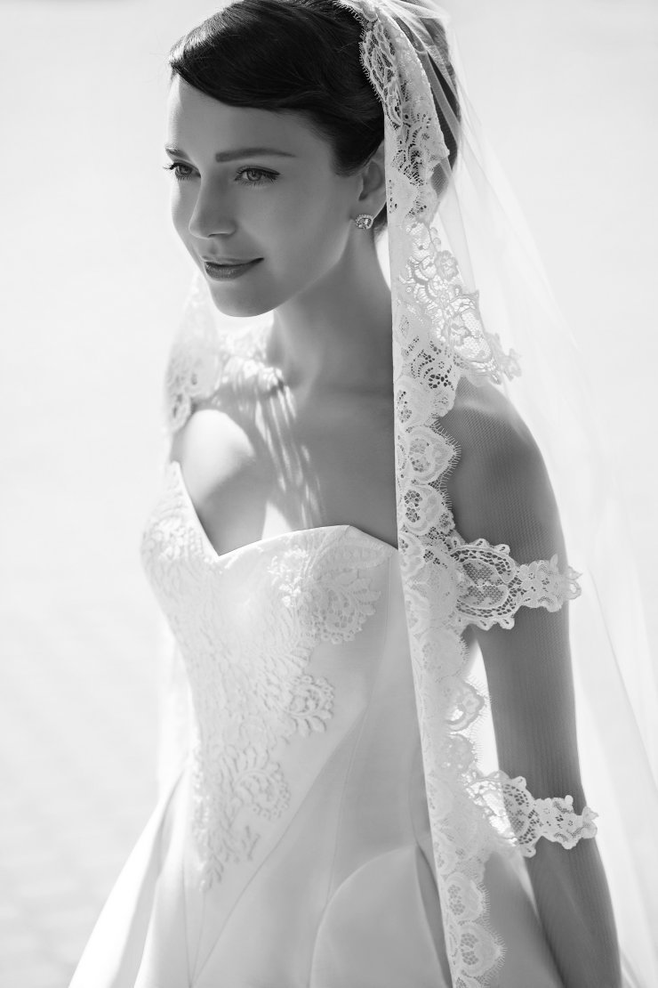 Нежный образ невесты - платье с геометричным V-образным, украшенное кружевом, которое перекликается с кружевом на длинной фате.  